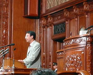 本会議場の演壇で質問する塩川議員